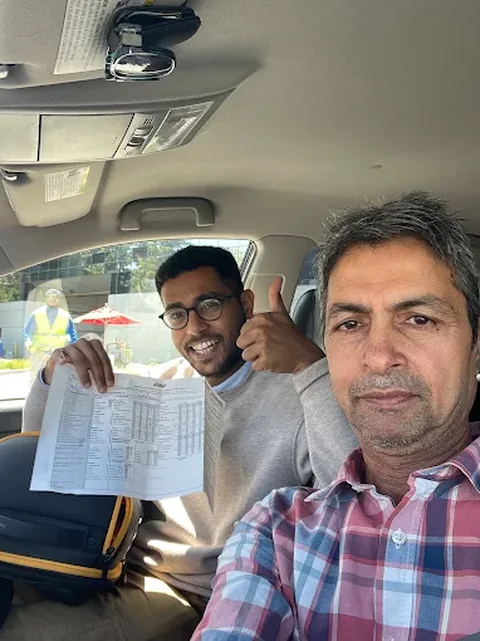Javed and a student giving a thumbs up with passed DMV drive test paperwork